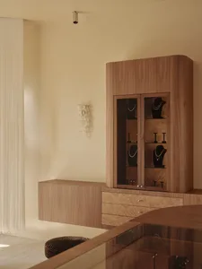 A dressing room with a wooden cabinet, soft warm lighting, and multiple necklaces hanging from it, creating a cozy atmosphere
