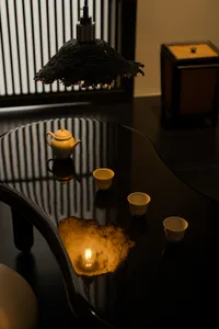 A traditional dining room with a wooden table and chairs, a tea set, and a vase, set in a dimly lit space with a warm and natural ambiance
