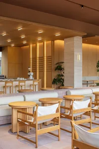 A modern restaurant interior with brown and white tables, brown chairs, and a warm atmosphere created by well-placed lighting
