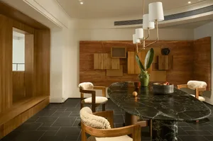 A modern kitchen with a black marble countertop, brown chairs, and a potted plant, set in a well-lit space with a warm atmosphere