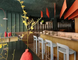 A modern kitchen with a dining table and chairs, featuring a counter with a vase, well-lit with natural sunlight and warm atmosphere