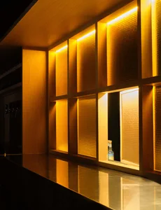 A casual bar scene with a wooden counter and a yellow bottle, set in a modern space with natural light from a window