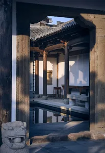 A traditional Asian-style building with a wooden structure and tiled roof, featuring a courtyard with a reflecting pool and outdoor furniture