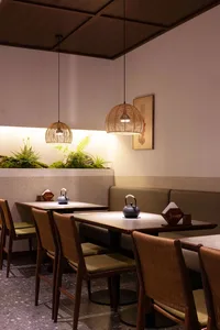 Cozy modern restaurant interior with dim lighting, artwork on the walls, and tables set with bowls and cups