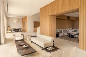 Comfortable living space with a large couch, coffee table, and dining table, decorated with various items and well-lit