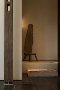 Cozy living area with a wooden floor, stone staircase, chair, and bench, lit by dim lighting