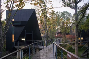 A black house with a triangle-shaped structure surrounded by trees, creating a serene atmosphere
