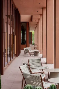 A modern outdoor dining space with a row of wooden chairs and white tables, set in a well-lit area with a comfortable atmosphere