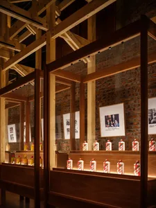 Photograph of a brick building with a wooden display case featuring a collection of bottles, set against a brick exterior