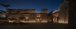 A dimly-lit brick building with a stone-like appearance and an arched doorway, photographed at night