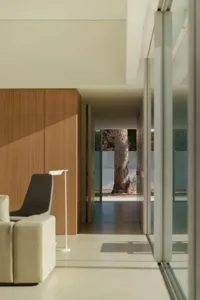 Cozy living room with a white color scheme, wooden furniture, and natural light from the glass doors
