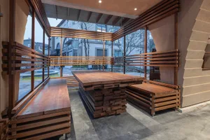 A warm and inviting dining area with a wooden table and bench, surrounded by a room with a window and a potted plant