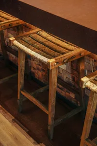 A wooden dining table and chairs in a restaurant setting, surrounded by a bench, creating a warm and inviting atmosphere for a relaxed dining experience