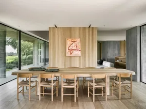 A warm and inviting dining room with a wooden table and chairs, a painting on the wall, and a wooden floor