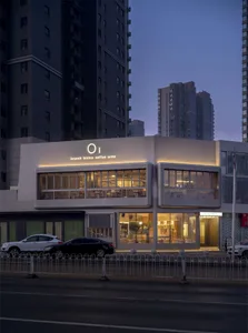 A modern cafe with a white facade and glass front, filled with furniture and natural light