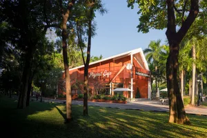 Photograph of a building with a large orange facade, featuring a restaurant or cafe with outdoor seating