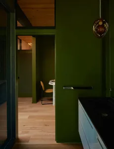 A well-lit bathroom with green walls, a black countertop, and a toilet, creating a bright and inviting atmosphere