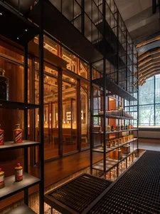 A cozy restaurant or store with a wooden floor, glass door, and a dining table and chairs, featuring a visually appealing display of bottles on shelves