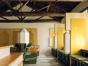 Cozy restaurant with wooden floor, vaulted ceiling, and wooden panel walls, dim lighting, and tables and chairs