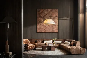 Cozy living room with a brown couch, a chair, and a coffee table, featuring a large painting on the wall and decorative items, with dim lighting creating a warm ambiance