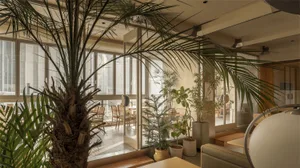 Cozy modern restaurant interior with potted plants, tables, and chairs, creating a lively atmosphere