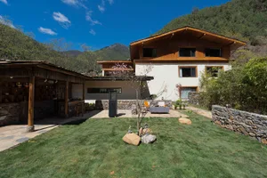 A two-story house with a wooden exterior, a large patio area, and potted plants, featuring a mix of natural and artificial lighting