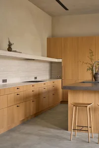 Modern kitchen with wooden cabinets, a sink, stove, and refrigerator, with natural light and two chairs