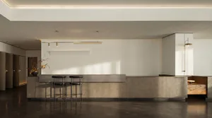 A well-lit industrial kitchen with a metal counter and black stools, likely in a restaurant or commercial space