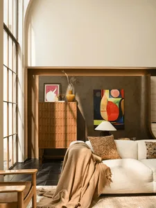 A modern living room with a white couch, a chair, and a potted plant, well-lit and welcoming
