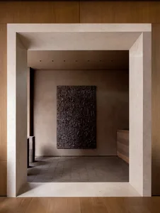 Warm and inviting study with a brown wooden floor, a large brown and black painting, and a wooden desk