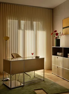 A modern study with a metal desk featuring a glass top, a chair, a vase with flowers, and a wine glass, set in a well-lit room with a stylish atmosphere