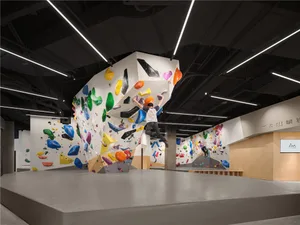 一間充滿光線的攀岩館，色彩繽紛的岩石牆、抓點和人工照明
