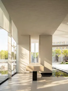 Large, modern lobby with a large window allowing natural light to fill the space, surrounded by concrete walls and bright lighting