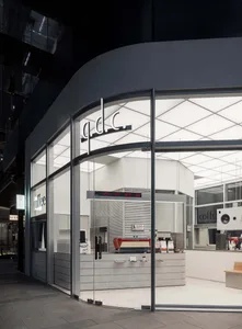 A well-lit coffee shop interior with a modern design, featuring a wooden counter, a coffee machine, and a few cups and a bottle on display