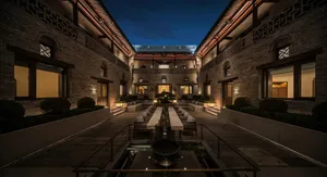 A large, well-lit building with a courtyard, stone, and wood materials, featuring a fountain and a blend of traditional and modern elements