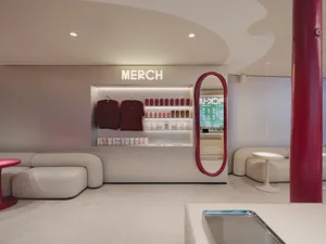 一間穿著現代風格的商店，白色主調，牆上掛著一面大鏡，展示著整齊排列的上衣