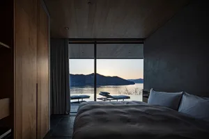 A well-lit bedroom with a large bed, white comforter, and natural light from a large window