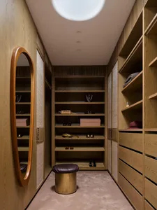 Dimly lit closet with wooden floor, mirror, shelves, and various items such as shoes and a handbag