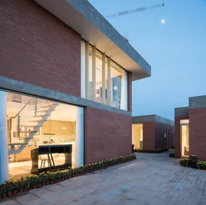 Large modern house with a glass wall, brick exterior, and open-plan living space with a fireplace, kitchen, and dining area