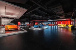 Black and white photograph of a modern sports car showroom with various sports cars on display, including a blue and red car, in an elegant and sophisticated setting