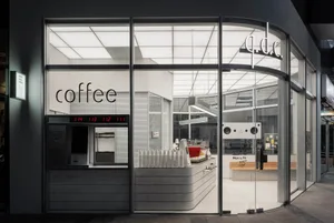 A modern coffee shop with a predominantly white interior, natural light, and various pieces of furniture