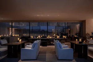 Modern living space with a large window, white furniture, and a fireplace, filled with natural light