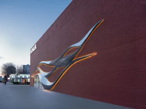 A modern commercial space with a red brick wall featuring a unique design, illuminated by light, and possibly a store or business center