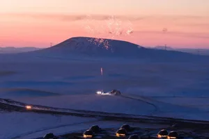 Snowy landscape with a mountain in the background, featuring small wooden cabins and a serene atmosphere