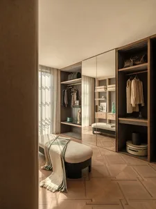 A modern bedroom with a wooden floor, a large mirror, and comfortable furniture, creating a bright and inviting atmosphere