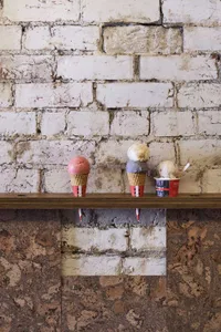 A casual photograph of a brick wall with three colorful ice cream cones placed on it