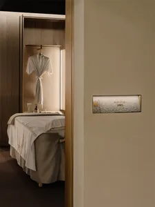A modern bedroom with a bed against the wall, a closet next to it, and a white sheet covering the bed, in a well-lit space