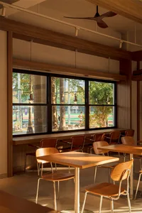 A restaurant with a wooden floor, chairs, and dining tables, well-lit by natural light from a large window