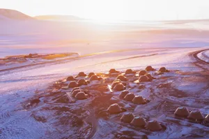 A serene snowy landscape with small, rustic wood cabins surrounded by snow, creating a peaceful atmosphere