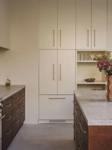 Bright modern kitchen with white wood cabinets, a marble countertop, and natural light from windows